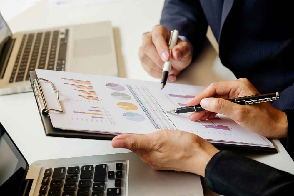 Dvoje poslovnih ljudi analiziraju grafove i rezultate – simbol mjerljivih uspjeha u poslovanju